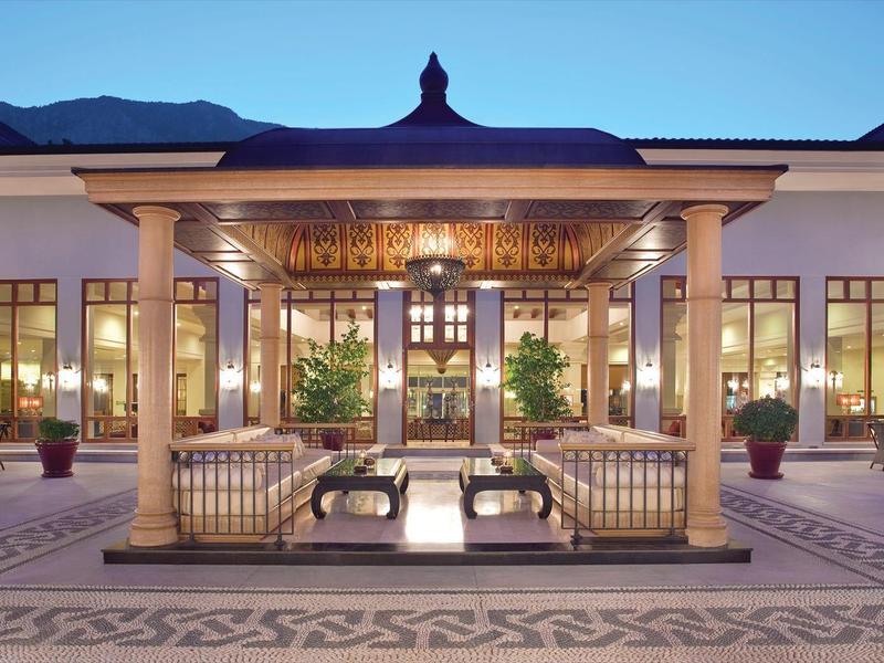 Elegant hotel courtyard with warm lighting, seating, and decorative water features at dusk.