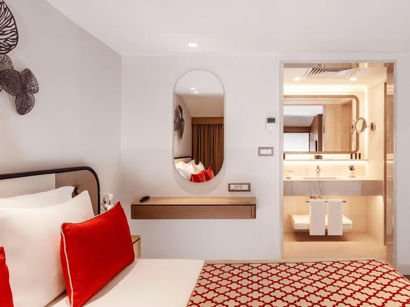 Bright deluxe double room with red patterned bedding and modern bathroom.