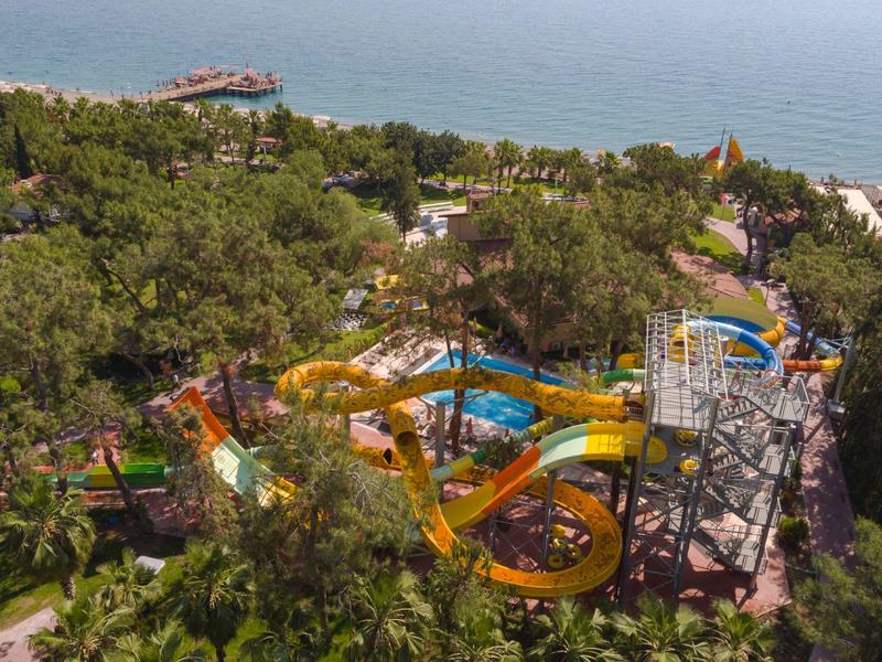 Aerial view of a water park with colorful slides, surrounded by trees and near a beach.