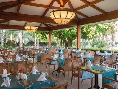 Terrasse de restaurant d'hôtel élégante avec tables dressées et vue sur un jardin verdoyant.