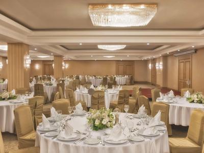 Chambre d'hôtel élégante avec grand lit, décor beige et vue sur jardin.