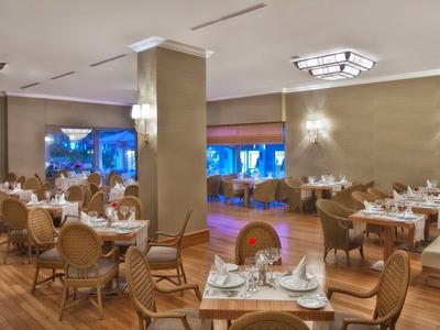 Salle de restaurant élégante avec tables en bois et grandes fenêtres lumineuses.