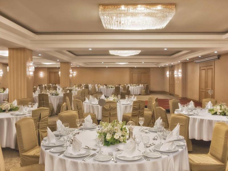 Chambre d'hôtel élégante avec grand lit, décor beige et vue sur jardin.