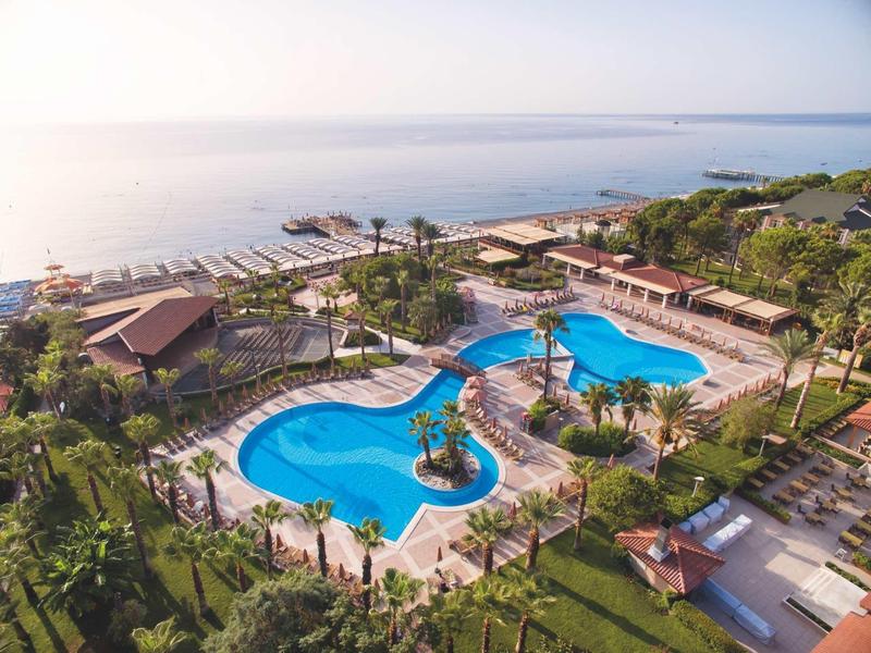 Complexe hôtelier avec piscine extérieure près de la plage et vue sur la mer calme.