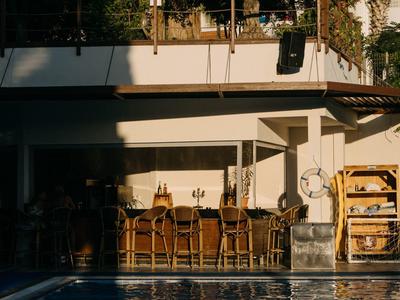 Bar na świeżym powietrzu z krzesłami i basenem, ciepła atmosfera o zachodzie słońca.