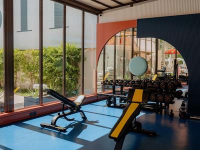 Moderne Trainingsgeräte in einem hellen Fitnessraum mit großen Fenstern und Blick nach draußen.