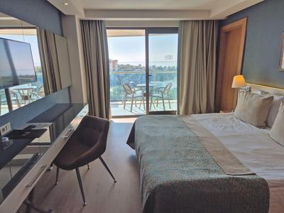 Nowoczesny pokój hotelowy z łóżkiem podwójnym i balkonem z widokiem na morze.