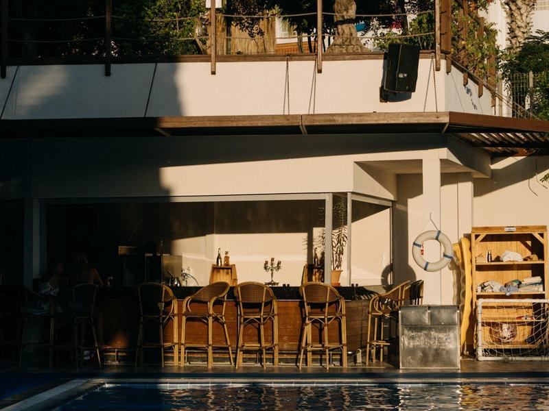 Bar na świeżym powietrzu z krzesłami i basenem, ciepła atmosfera o zachodzie słońca.