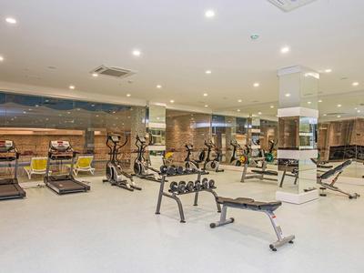 Sala palestra moderna con varie attrezzature da allenamento e illuminazione luminosa.