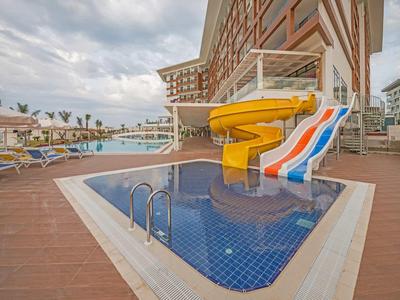 Piscine vide avec toboggans colorés et transats dans un complexe hôtelier.