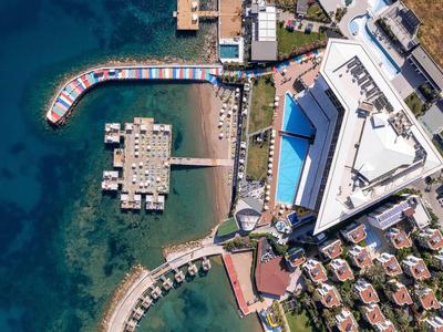 Vue aérienne d'un hôtel avec piscine, transats et jetée privée au bord de la mer