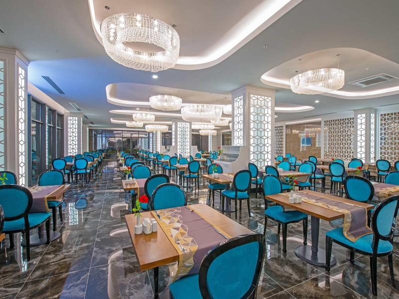 Grande salle à manger élégante avec des chaises bleues et des tables en bois dans un hôtel.