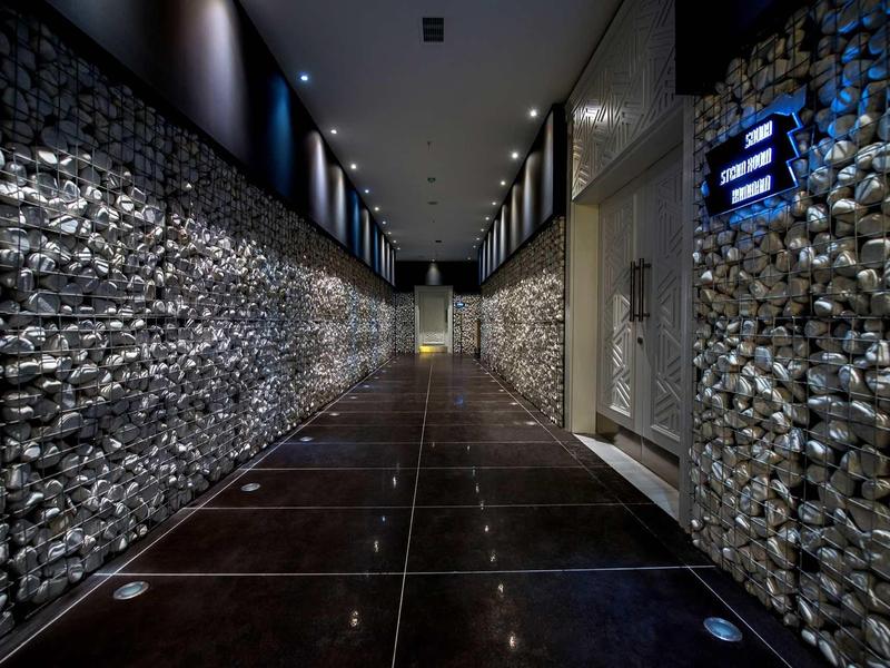 Couloir d'hôtel moderne avec murs en pierre décoratifs et sol sombre.