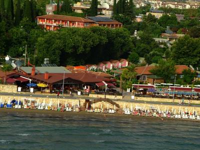 Spiaggia con sdraio e edifici sullo sfondo lungo la costa.