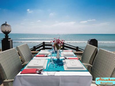Un tavolo apparecchiato su una terrazza con vista sul mare sotto un cielo azzurro.