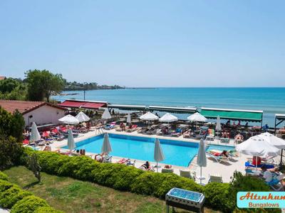 Vista di una piscina dell'hotel con ombrelloni e lettini vicino al mare sotto un cielo limpido.
