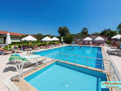 Grande piscina all'aperto con ombrelloni e sdraio in un giardino dell'hotel sotto un cielo azzurro.