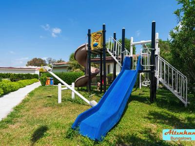 Area giochi con scivoli e struttura per arrampicata in un parco verde in una giornata soleggiata