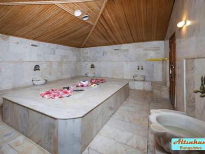 Un lussuoso bagno turco in marmo con una piattaforma centrale e petali di rosa.