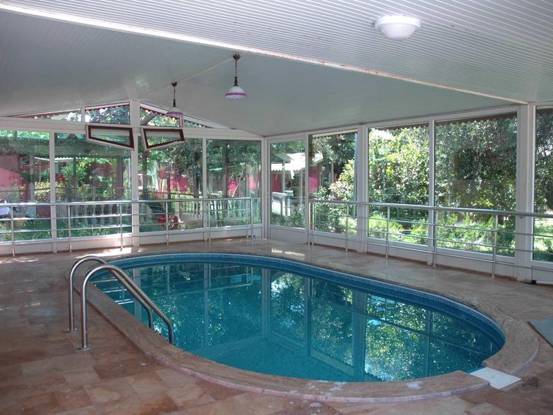 Piscina interna dell'hotel con grandi finestre che si affacciano sul giardino.