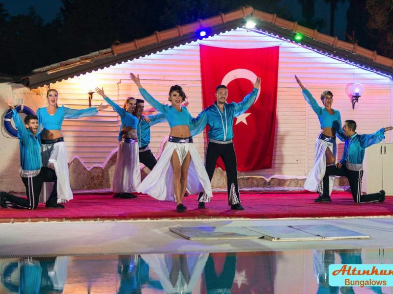 Gruppo in abiti tradizionali turchi danza davanti a un edificio con la bandiera turca.