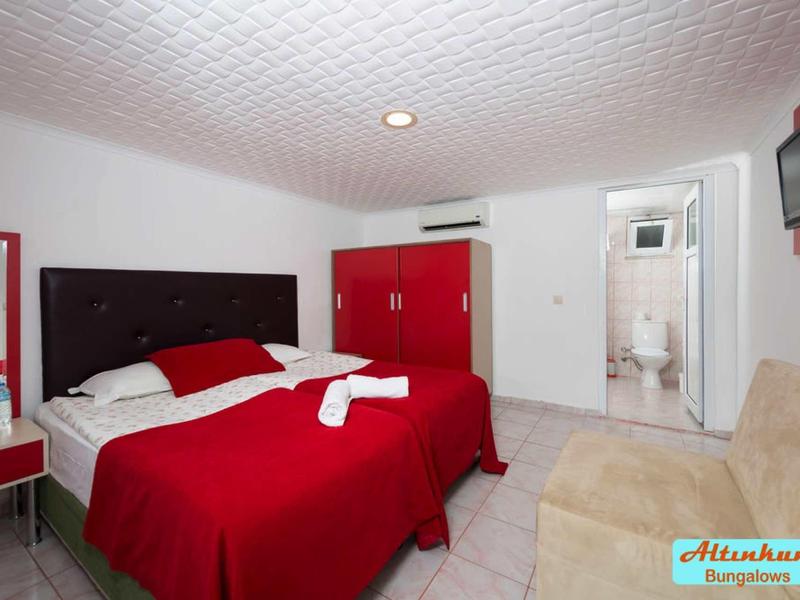 Camera d'hotel moderna con letto matrimoniale, biancheria rossa, armadio e accesso al bagno.