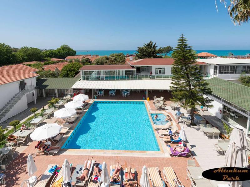 Pohled na hotelový bazén s lehátky a výhledem na moře v pozadí.