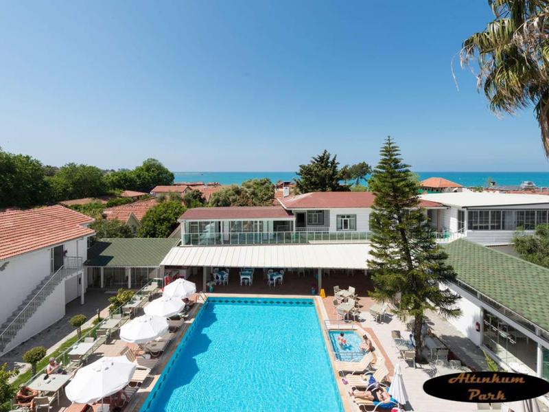 Hotel s bazénem, slunečníky a výhledem na moře a modrou oblohu.