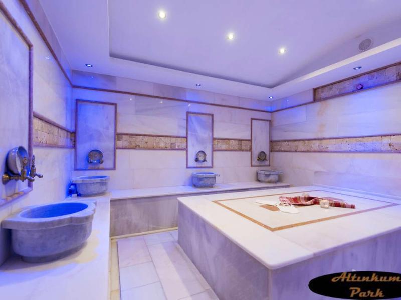 Moderní hammam s vyhřívaným mramorovým stolem, umyvadly a atmosférickým osvětlením.