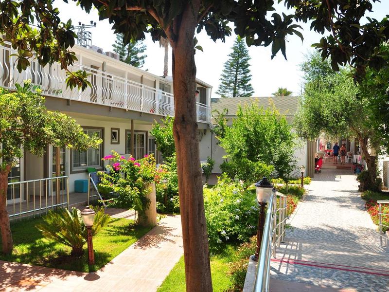 Hotelové nádvoří se zahradou, stromy a cestami mezi budovami.