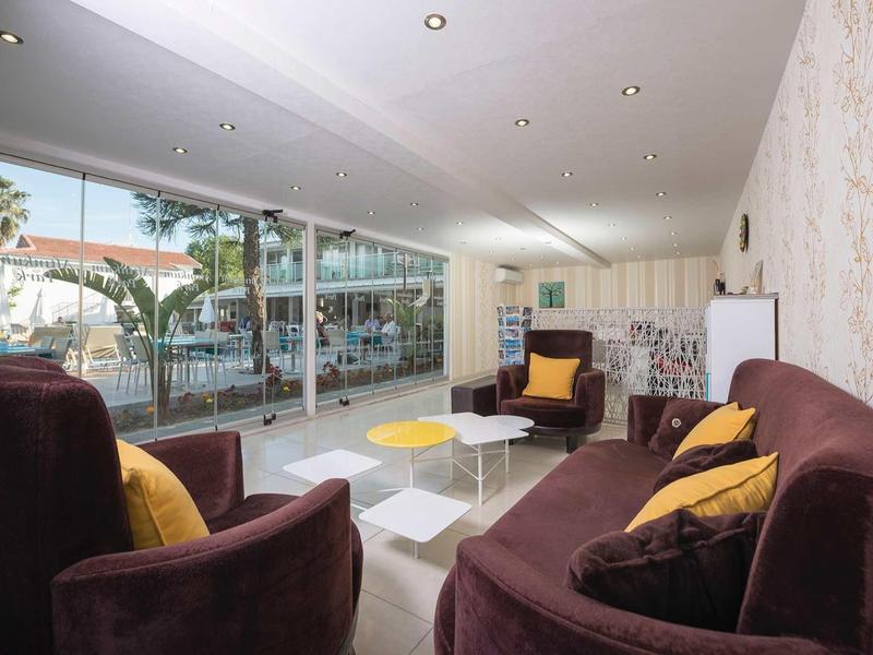 Pohodlná sedací část s hnědými pohovkami a velkými okny s výhledem na bazén.