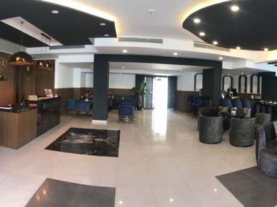 Moderna zona de vestíbulo de hotel con áreas de estar, plantas y suelo de mármol claro.