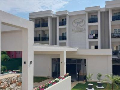 Complejo hotelero moderno con edificios de varios pisos, zona de jardín y macizos de flores decorativos a la luz del día.