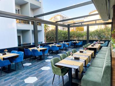 Área exterior moderna de hotel con sillas azules y verdes y suelo gris.