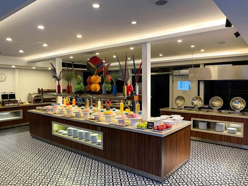 Area buffet in un hotel moderno con varie opzioni di frutta e colazione.