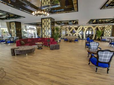 Großer, heller Raum mit Holzboden, blauen Sitzstühlen, roten Sofas und modernen Spiegeldecken.