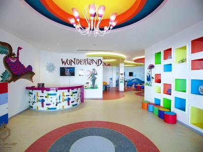 Bunte, kinderfreundliche Empfangshalle mit rundem Tresen, Hockern und verspielter Wandgestaltung.