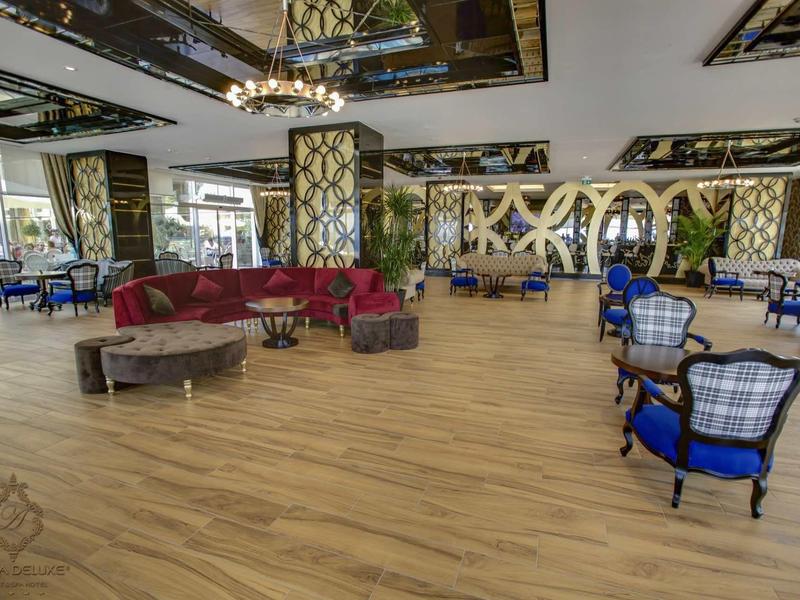 Prostorný světlý hotelový salonek s dřevěnou podlahou a elegantní modré křesla.