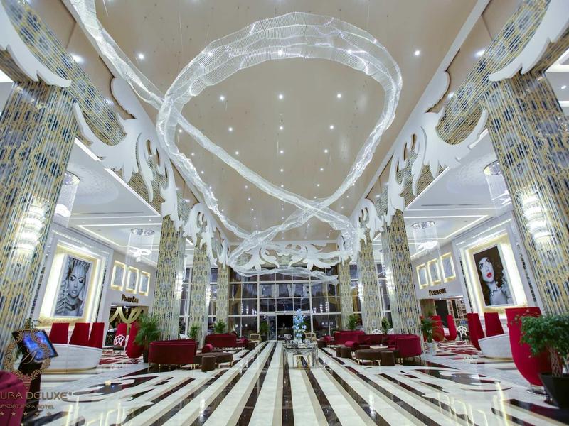 Velká luxusní hotelová hala s dekorovanými sloupy a mramorovou podlahou.