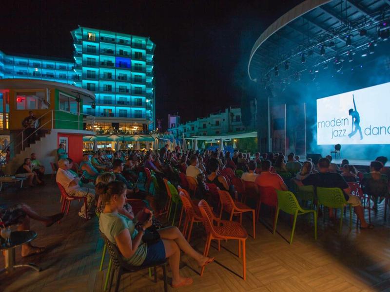 Večírek pod širým nebem s publikem sedícím před velkou jasnou obrazovkou na moderním dvoře.