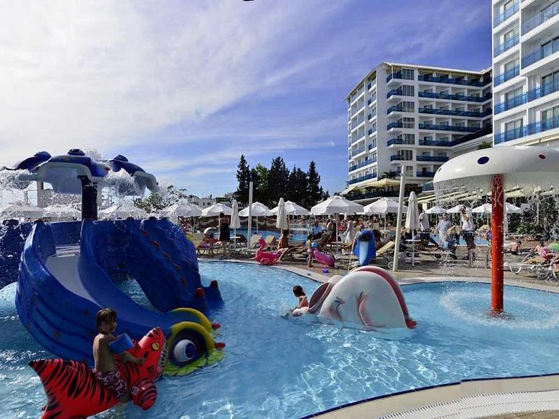 Venkovní bazén s tobogánem, vodními atrakcemi a hotelovými lehátky.
