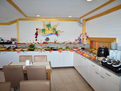 Area buffet con vari cibi e bevande in una stanza luminosa con posti a sedere.