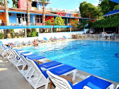 Area piscina animata con sedie a sdraio blu e hotel su più piani sullo sfondo.