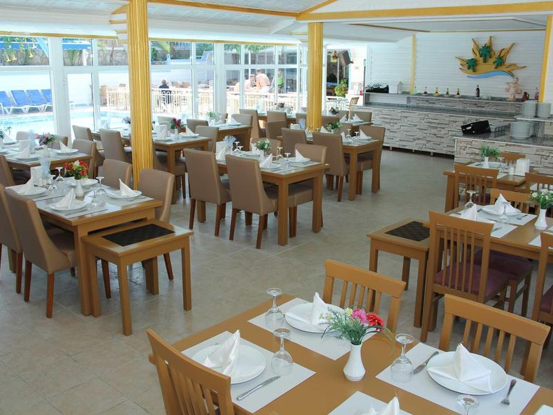 Ristorante luminoso con tavoli e sedie in legno apparecchiati con tovaglie e tovaglioli bianchi.