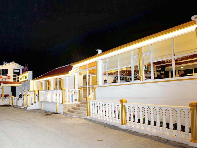 Complesso alberghiero illuminato con veranda e balaustra bianca di notte.