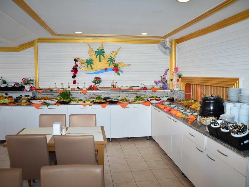 Area buffet con vari cibi e bevande in una stanza luminosa con posti a sedere.