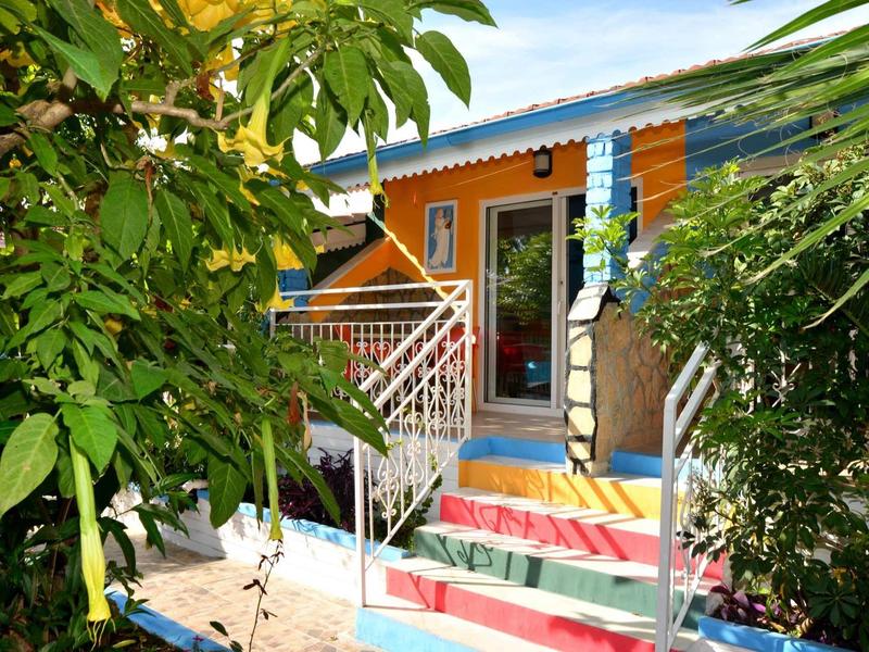 Ingresso colorato di un edificio con piante e cielo azzurro sullo sfondo.