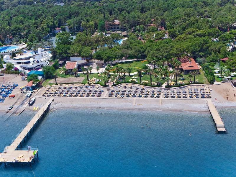 Beach with sun loungers and umbrellas along the coast with two long piers extending into the water.