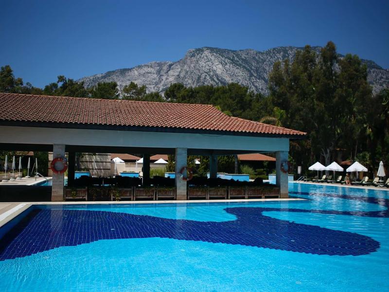 Large pool in front of a covered pavilion with mountains in the background