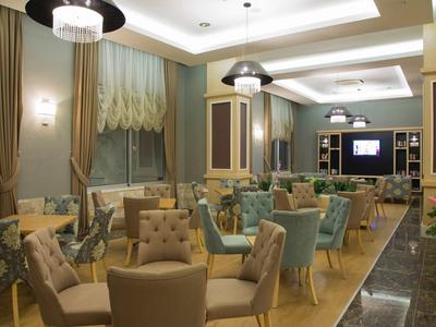 Elegantes Café mit bequemen Sesseln, Tischen und warmem Licht, moderne Deckenbeleuchtung.